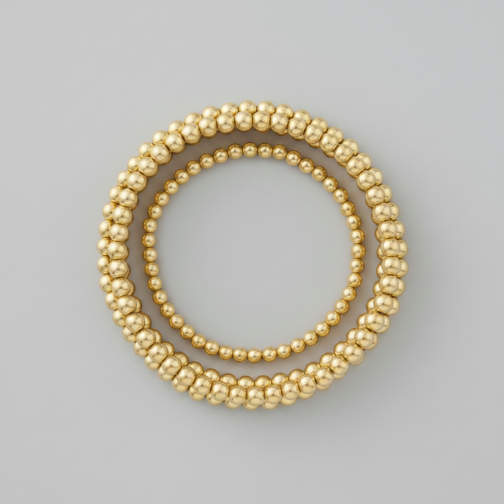 Miss Stack — four gold-filled stretch bracelets in graduating bead sizes laid in a perfect circle on light gray background